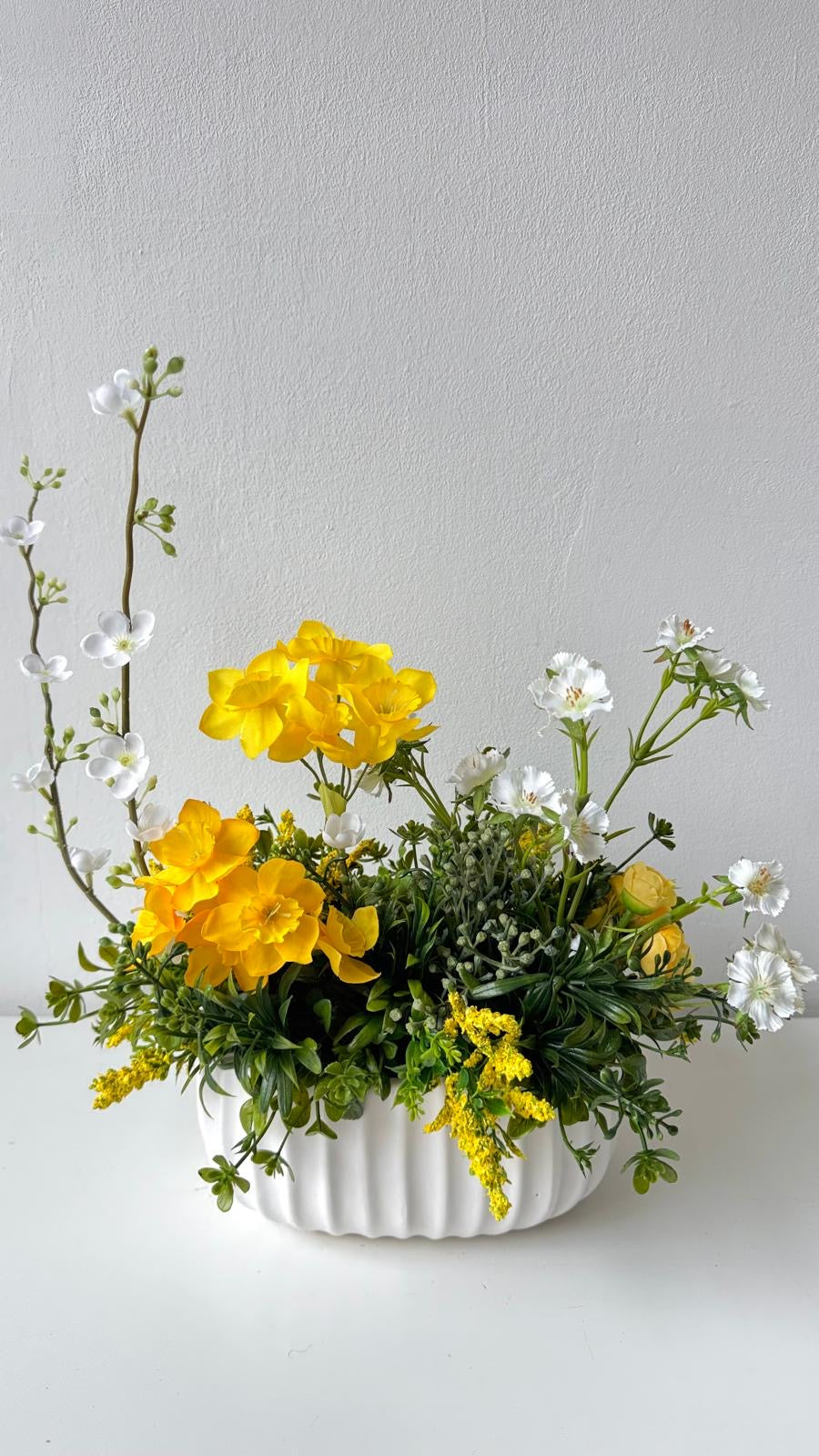 Frühlingshafte Tischdekoration mit weißen und gelben Blumen